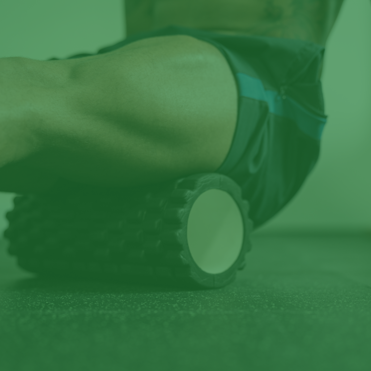 Deportista sometiéndose a fisioterapia, con el muslo sobre un rodillo. Filtro verde oscuro